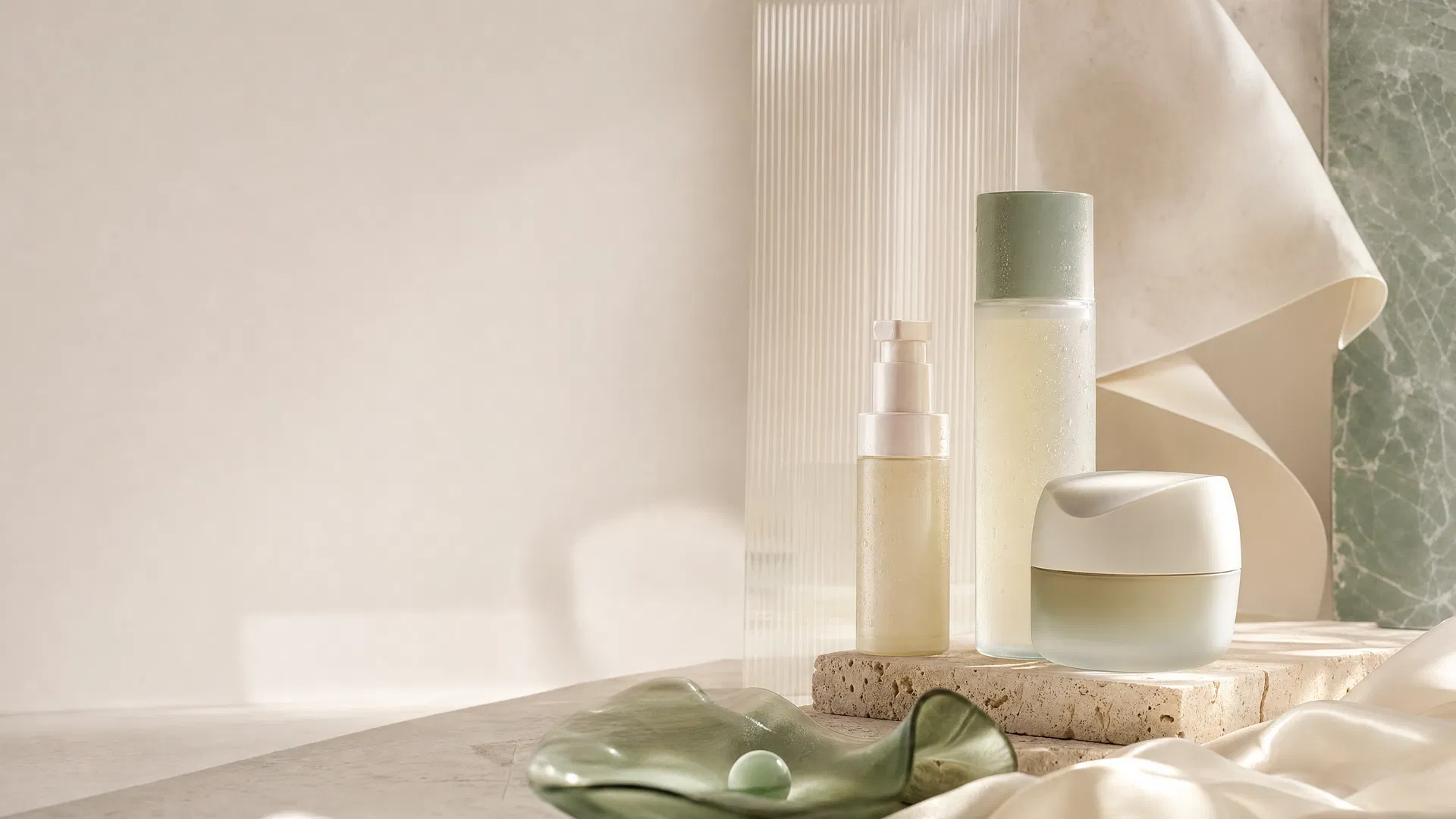 Minimalist luxury skincare bottles in cream and jade tones