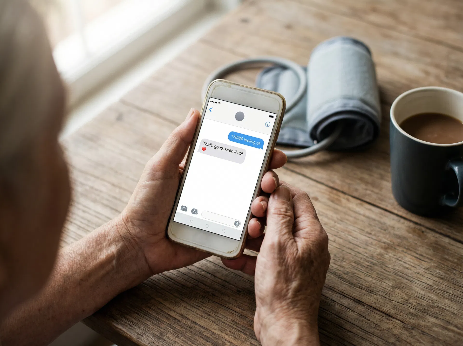 Elderly person texting blood pressure reading on a simple phone