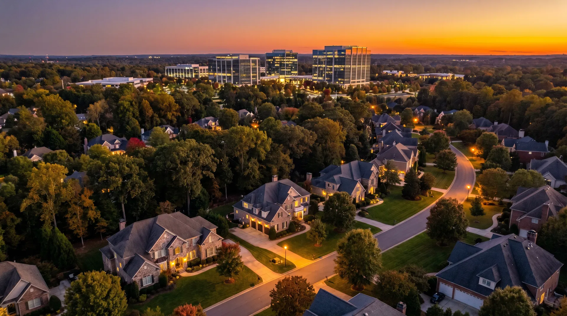 Aerial twilight view of Ballantyne neighborhood in south Charlotte NC with luxury homes and Corporate Park office towers glowing at sunset