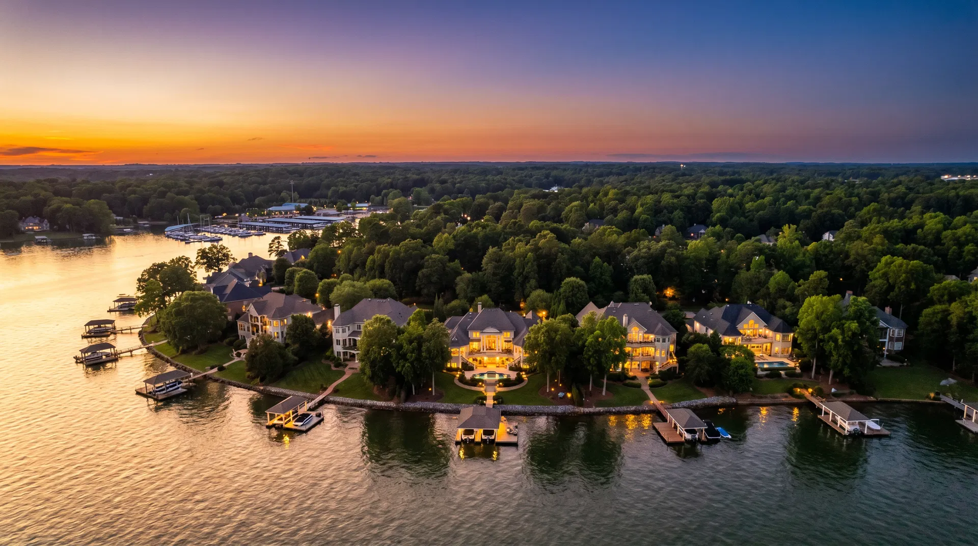 Aerial twilight view of Huntersville NC luxury lakefront homes on Lake Norman with boat docks glowing at sunset