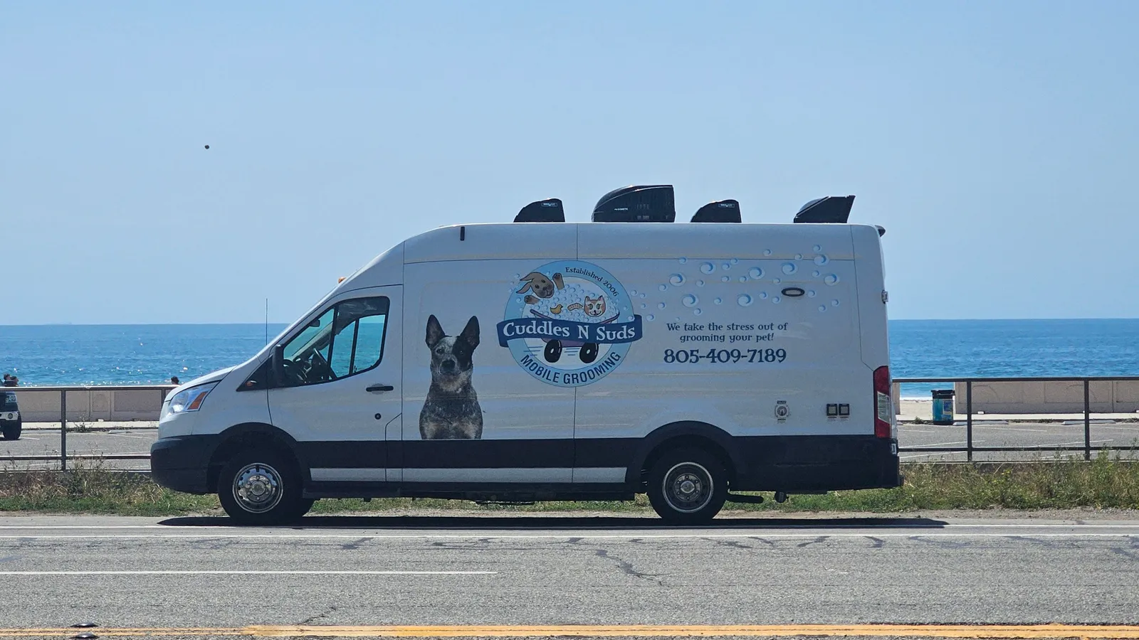Cuddles N Suds mobile pet grooming van in Malibu, California, with blue heeler graphic.