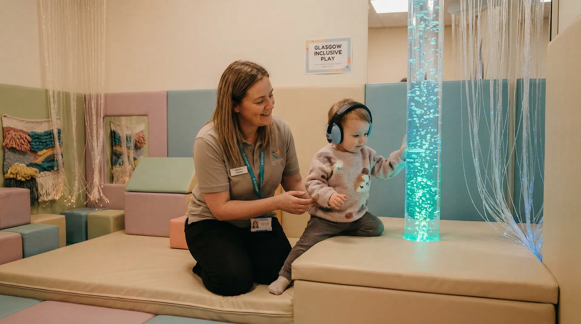 Child with sensory headphones exploring a calming sensory play area with bubble tubes and fibre optic lights at an inclusive Glasgow soft play centre