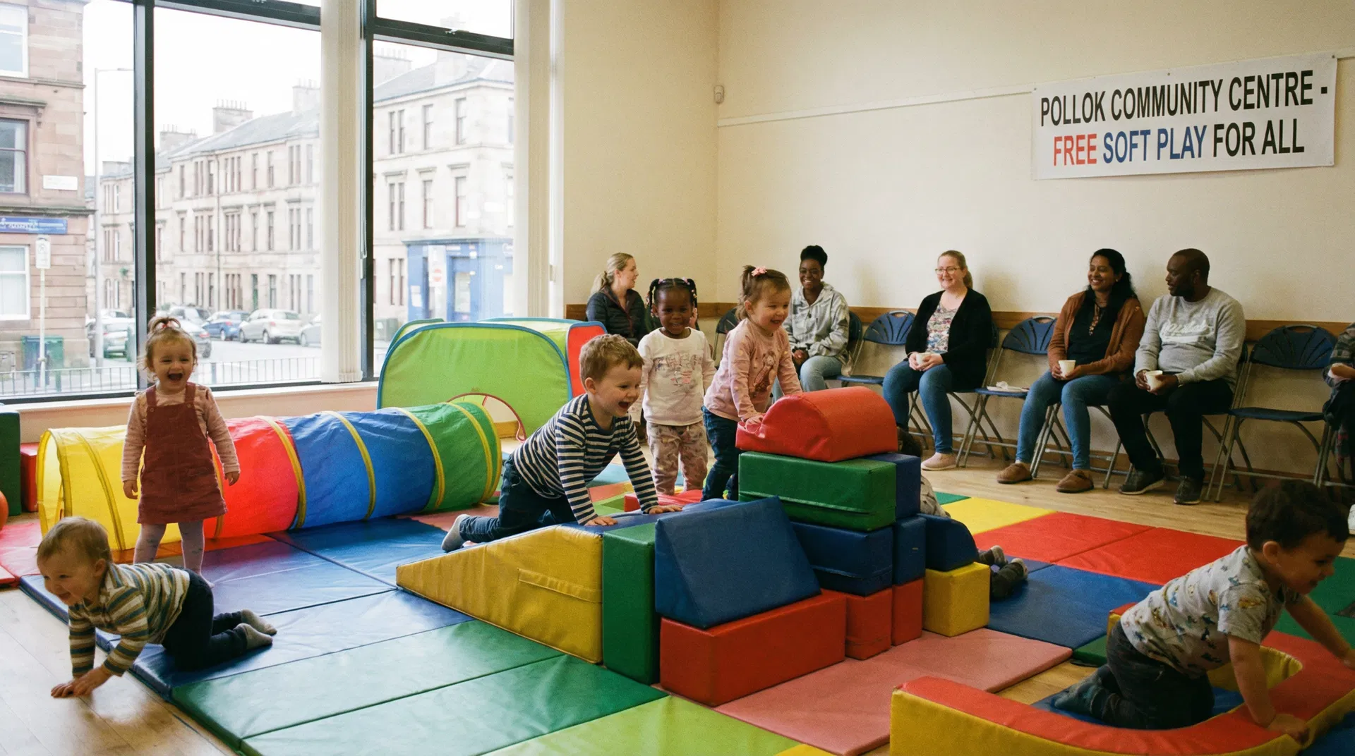 Children playing happily at a free community soft play session in a Glasgow community centre with colourful foam mats and equipment