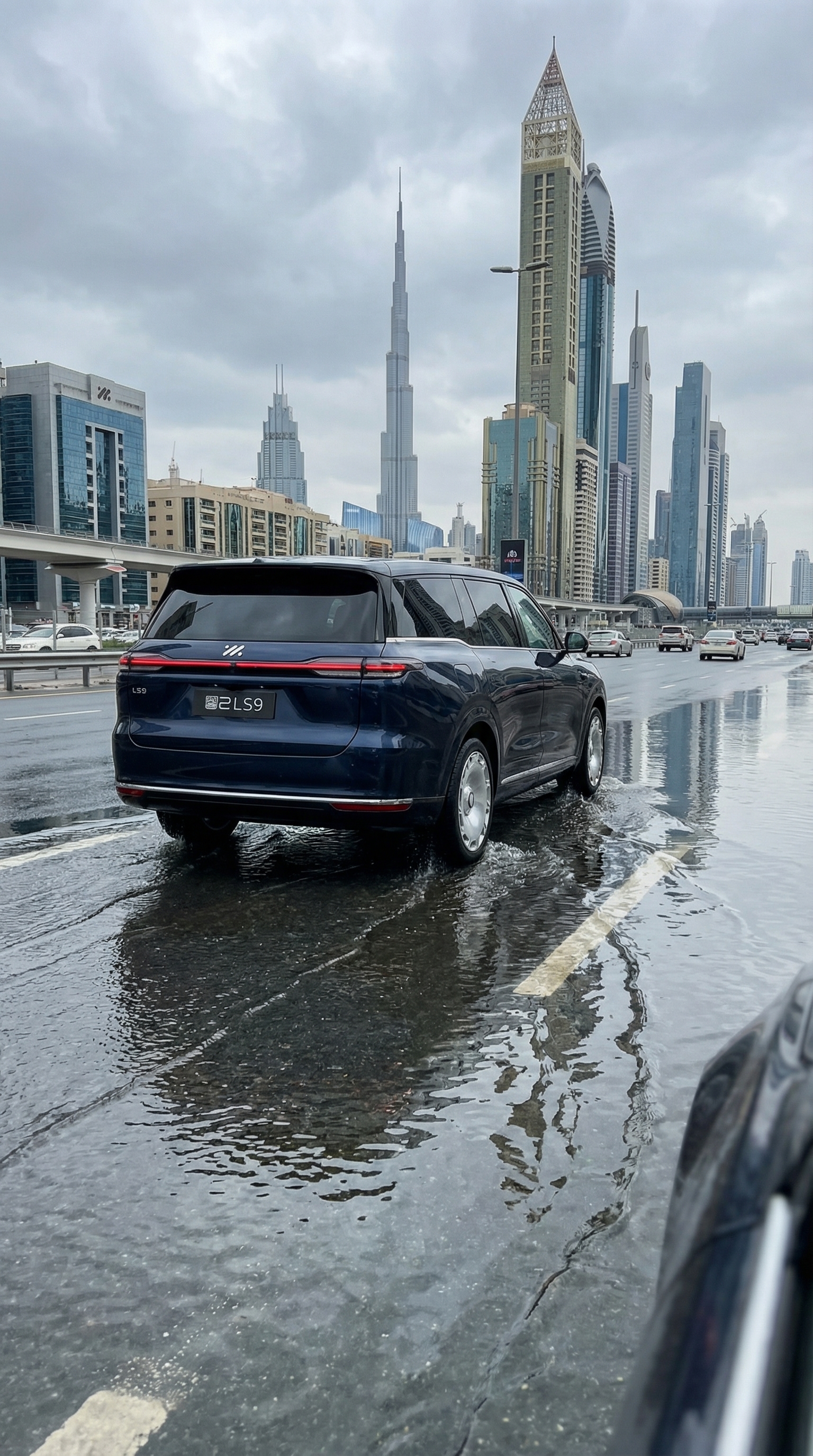 IM LS9 driving steadily through shallow flood water on Sheikh Zayed Road, rear three-quarter trackin
