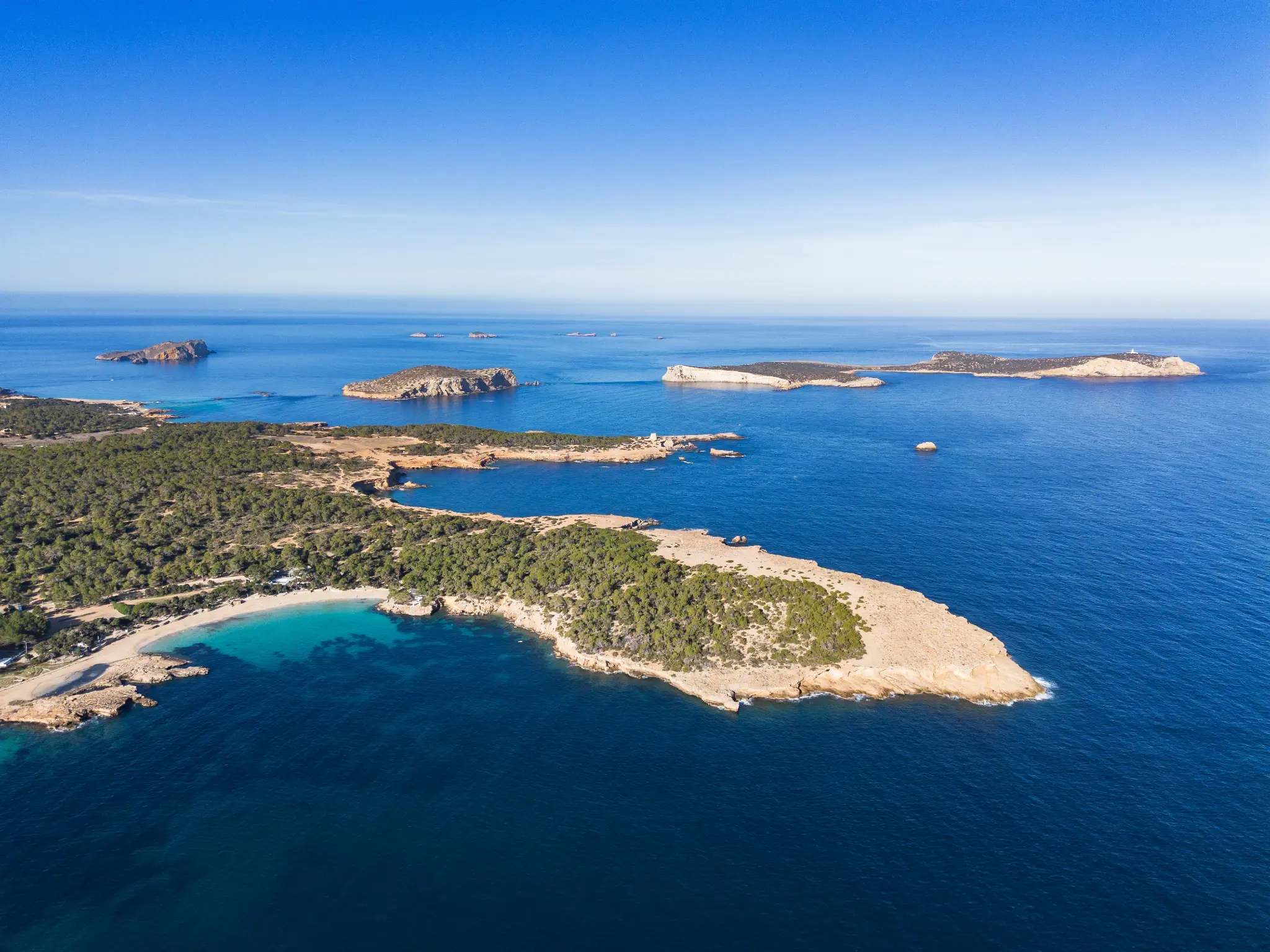 Aerial view of Ibiza's turquoise coastline with luxury yachts anchored in a secluded cala
