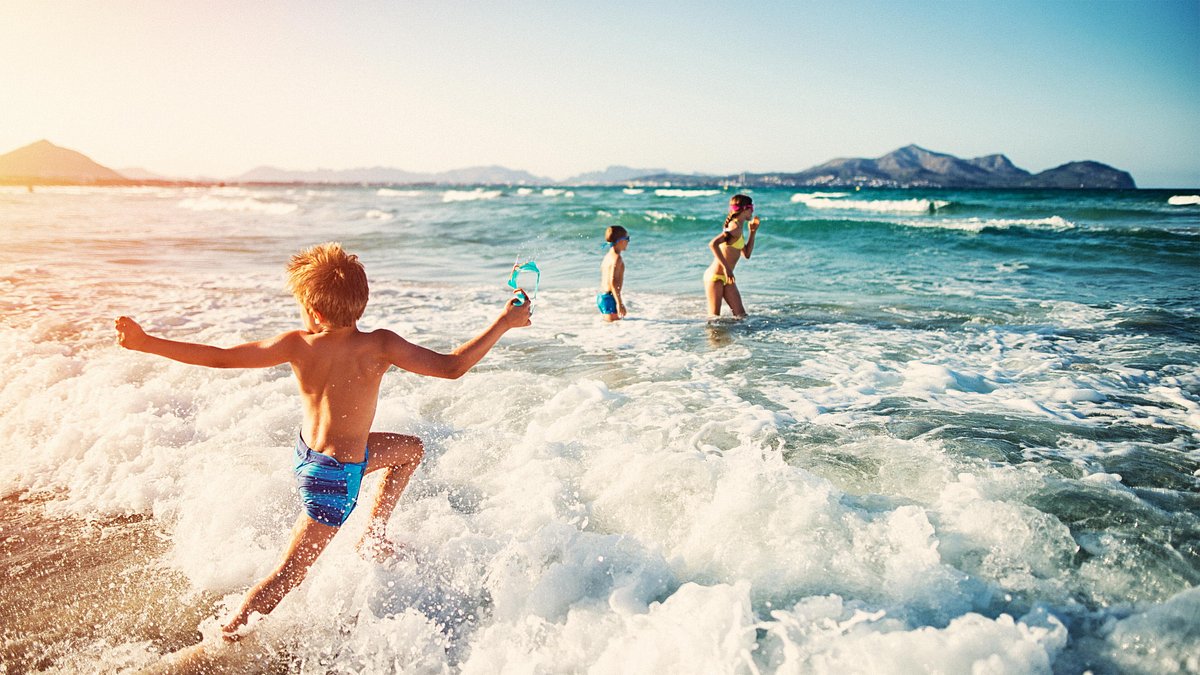 Family enjoying the warm waves on a golden Ibiza beach at sunset