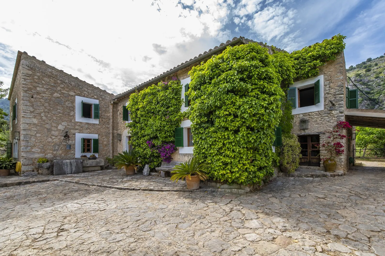 Traditional stone country house with green shutters and a cobbled courtyard in Selva, Mallorca