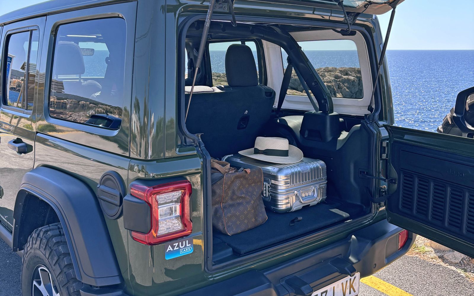 Bagagem na bagageira aberta de um Jeep Wrangler Rubicon num miradouro costeiro