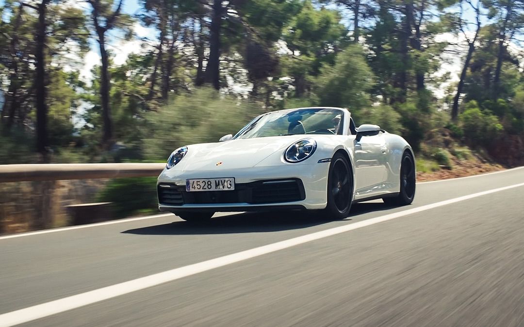 Vit Porsche 911 Carrera Cabriolet på en trädkantad väg på Mallorca