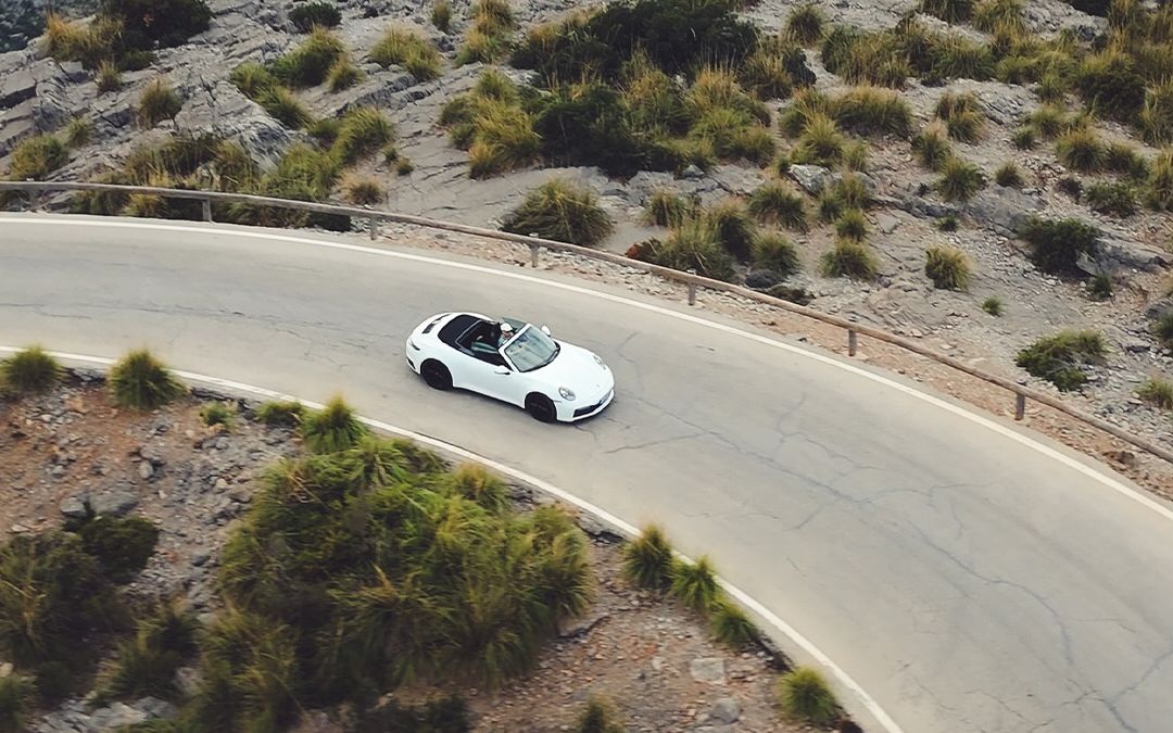 Vit Porsche 911 Carrera Cabriolet på en slingrande bergsväg på Mallorca