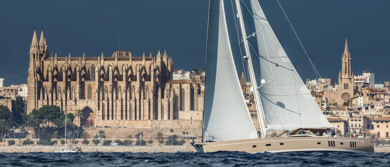 Sailing yacht on the water near Palma de Mallorca with people aboard, their faces not prominent.