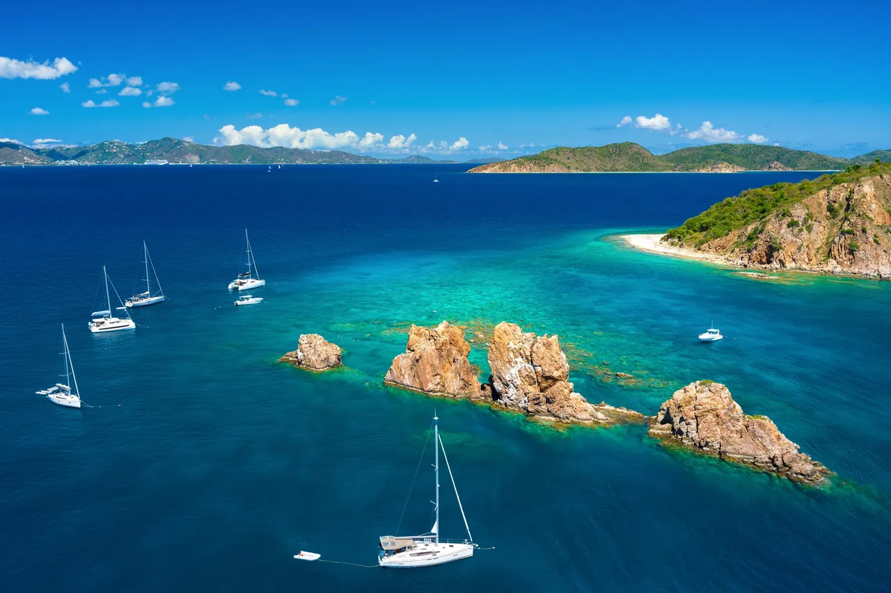 Aerial view of sailing yachts and catamarans anchored near The Indians rock formations in the British Virgin Islands.