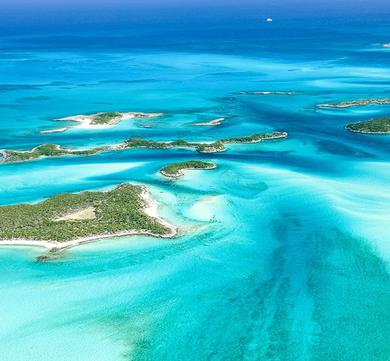 Aerial view of green Exuma Cays and turquoise water channels in the Bahamas, with no people visible.