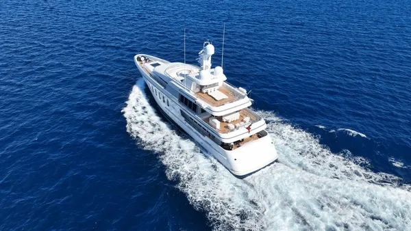 Aerial view of a white luxury motor yacht cruising through open sea.