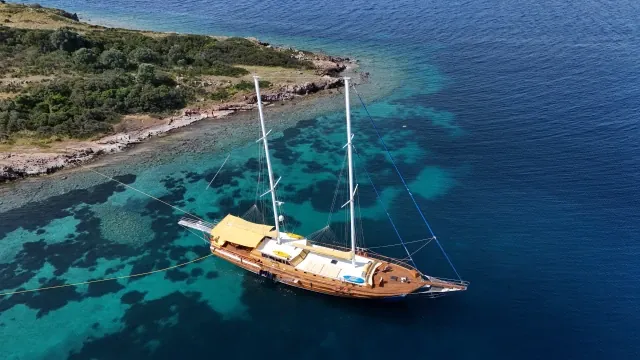 Classic wooden sailing yacht at anchor in clear turquoise water