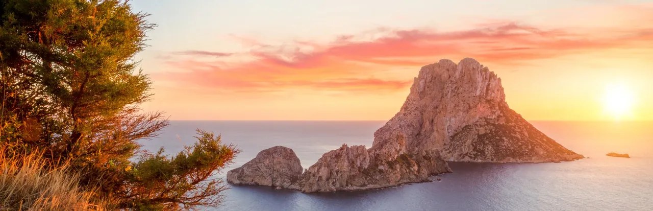 Aerial view of Es Vedrà island off Ibiza at sunset, with no people visible.
