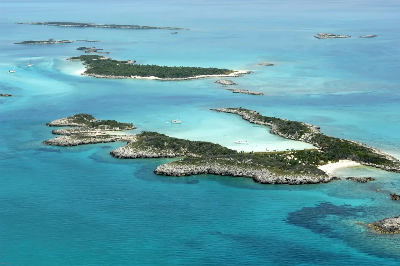 Aerial view of turquoise water, remote sandbars, tropical islands and anchored yachts in the Exuma Cays, Bahamas.