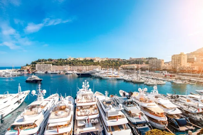 Luxury yachts docked in Port Hercule, Monaco, viewed from above across the marina.