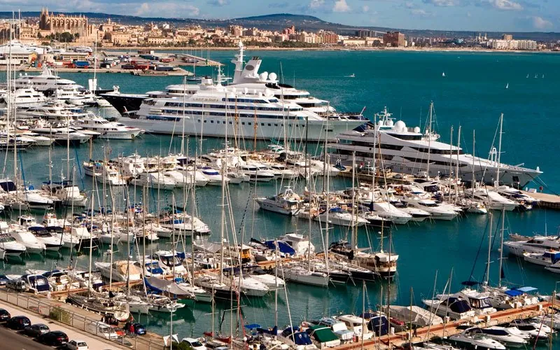 Luxury yachts, including Lady Moura, docked in Palma de Mallorca with the Gothic cathedral behind.