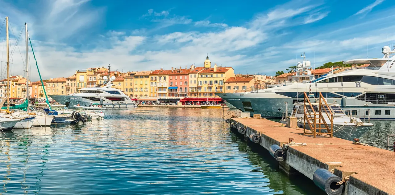Luxury yachts beside colourful waterfront buildings in the Saint-Tropez marina, France.