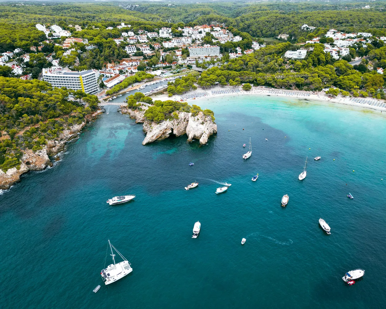 Aerial view of yachts and motorboats anchored in turquoise water at Cala Galdana, Menorca.