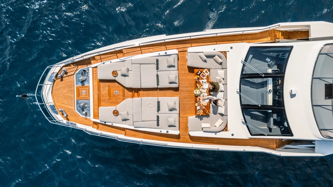 Guests on a superyacht foredeck with sunpads and a dining table