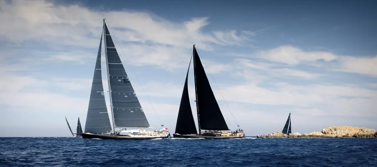 Luxury sailing yachts with black and grey sails, with people visible on deck