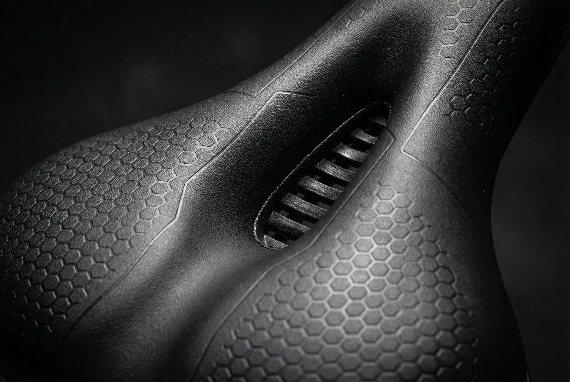 Close-up detail of the Ascent Saddle showing the deep pressure relief channel and hexagonal grip texture