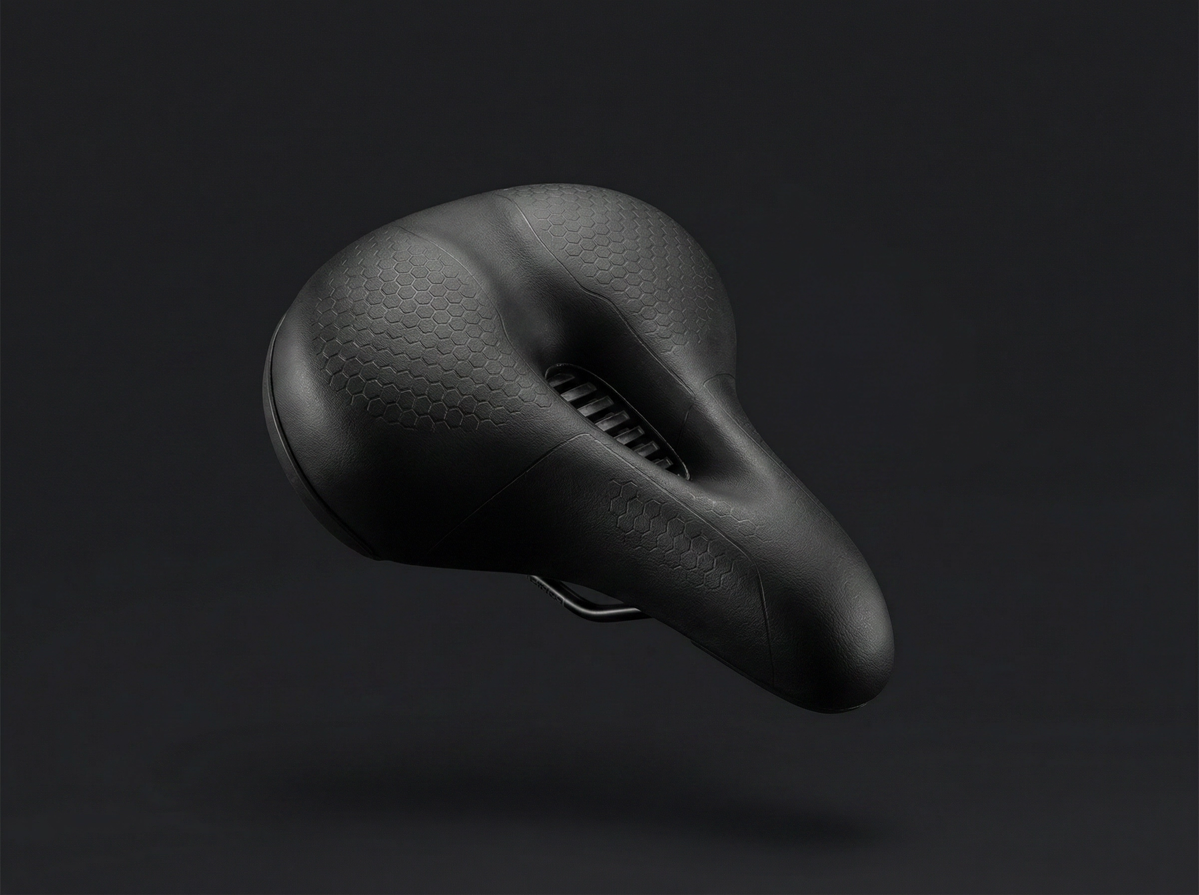 The Ascent Saddle — floating product shot showing wide sit bone support and pressure relief channel