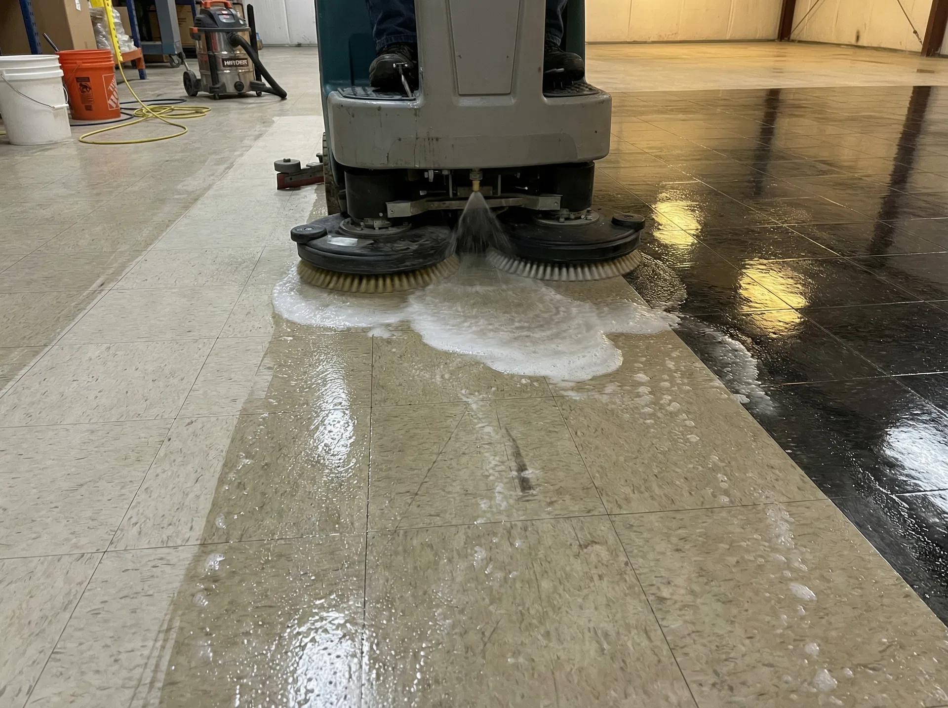 Professional floor stripping process — automatic scrubber removing old wax layers from commercial VCT tile