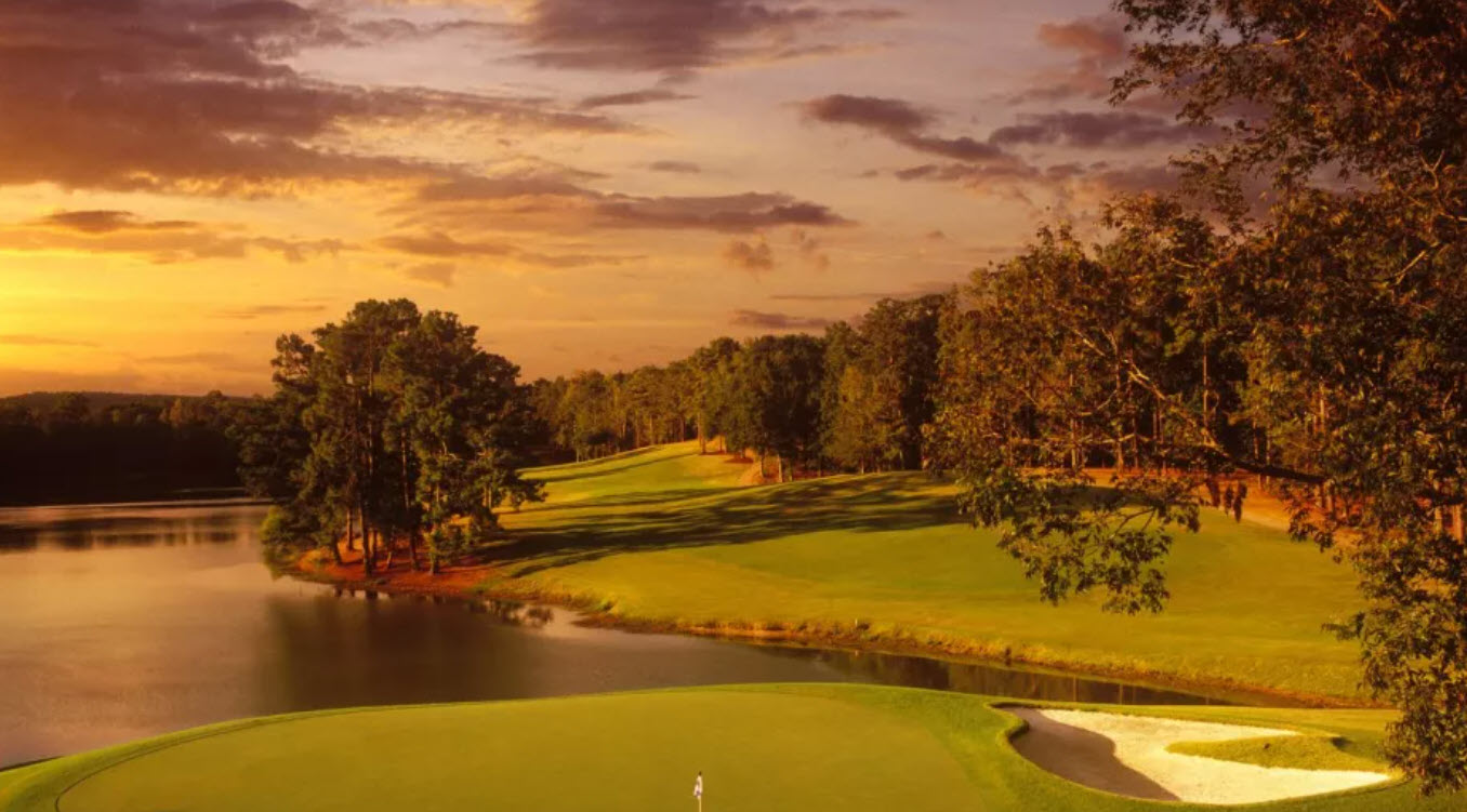 Scenic view of the 18th hole at Callaway Gardens Mountain View golf course with water in the foreground and green fairways leading to the clubhouse.