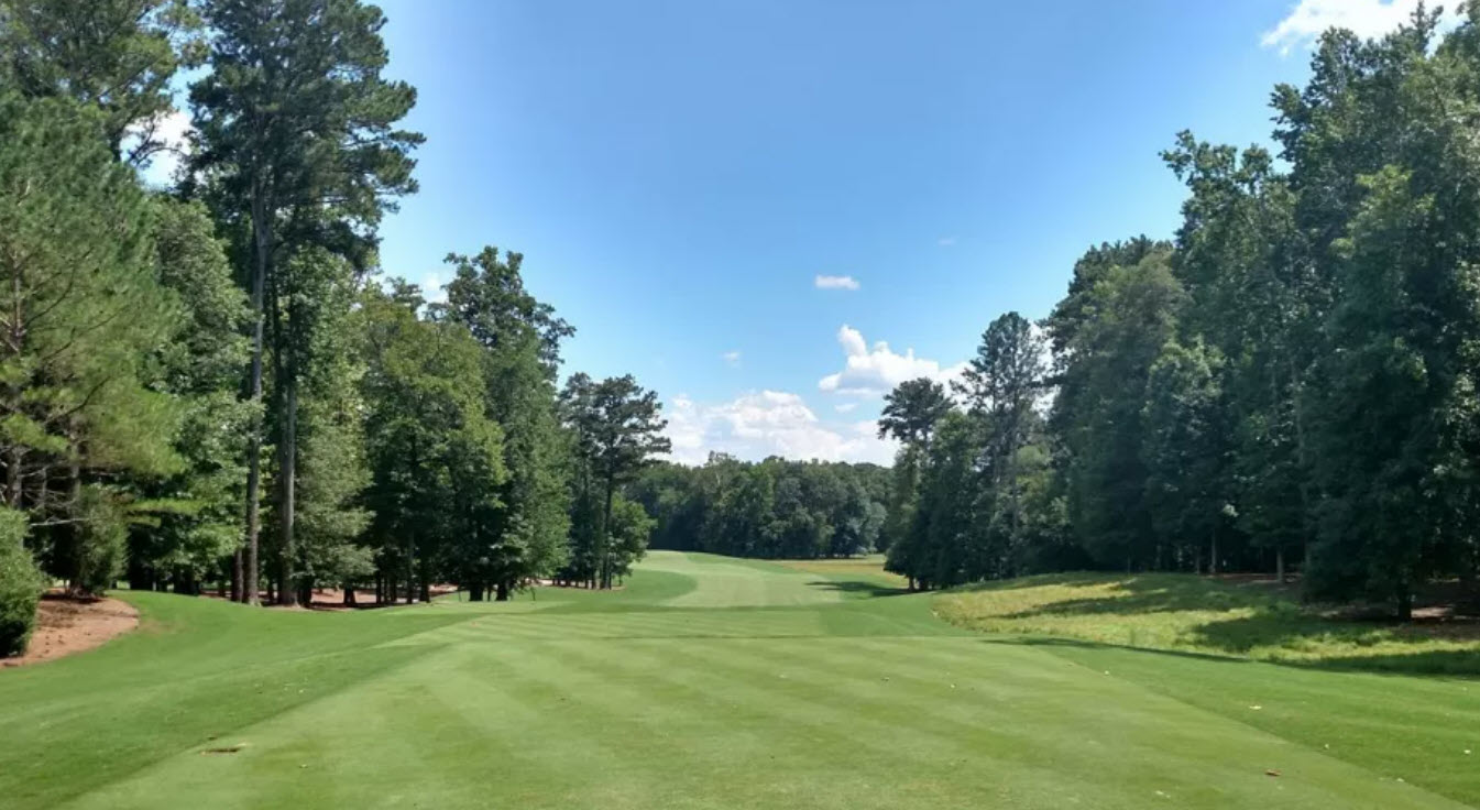 Aerial view of a pristine golf course fairway winding through mature trees at Capital City Club Crabapple Course