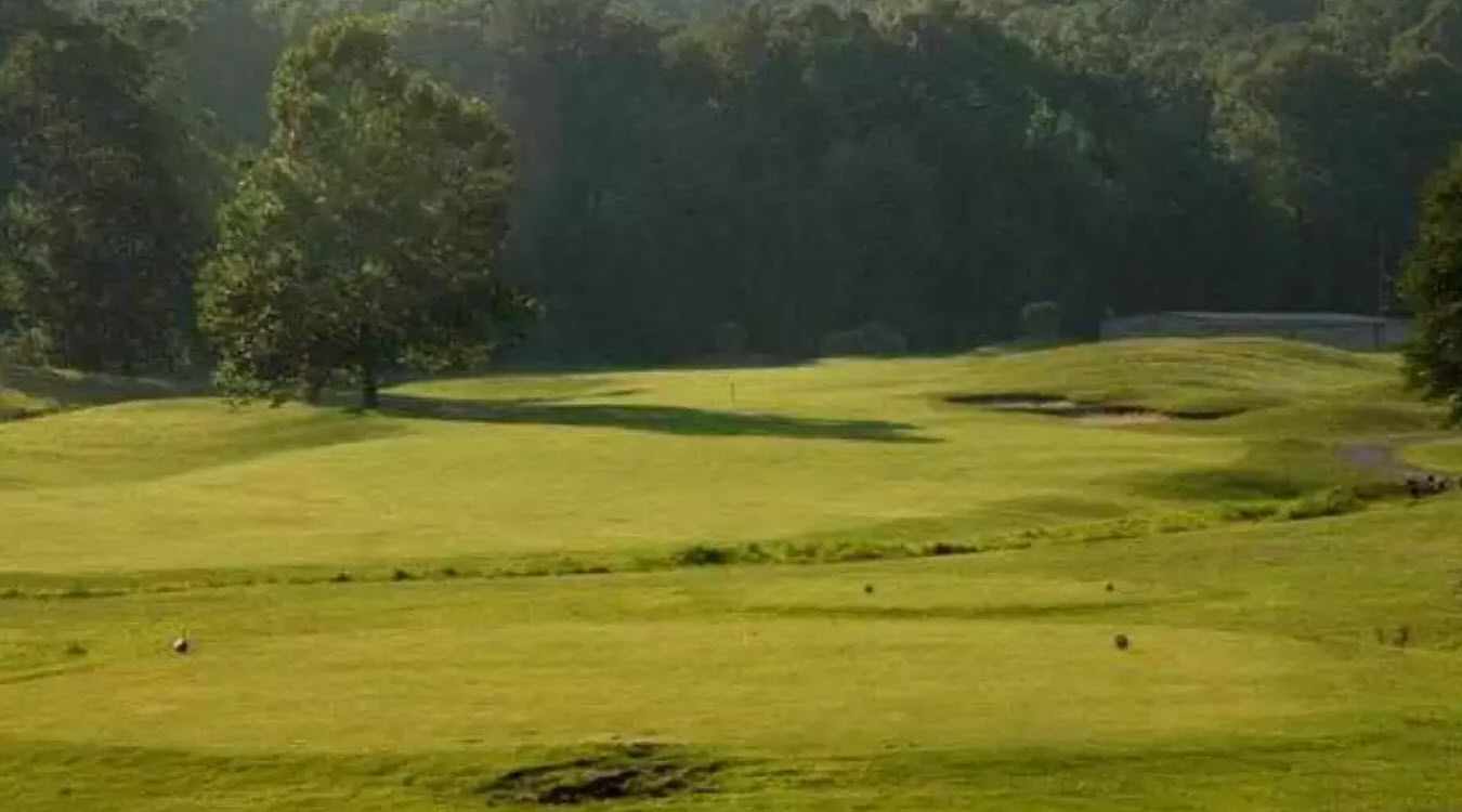 Scenic view of a green and fairway at Crooked Creek Golf Club with mountains in the background