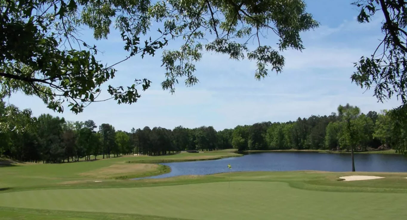 Panoramic view of a green and fairway at Keith Hills Country Club with mature trees and blue sky