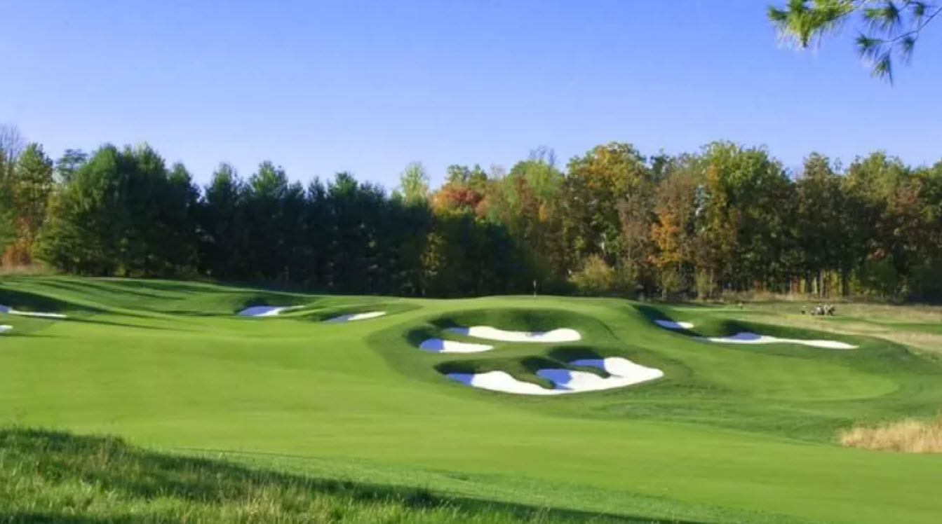 Panoramic view of a lush green fairway at Laurel Hill Golf Club with mature trees and a clear blue sky