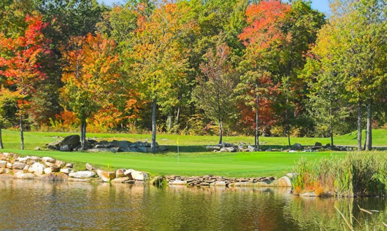 Panoramic view of Mystic Rock golf course with rolling hills and lush green fairways under a clear blue sky