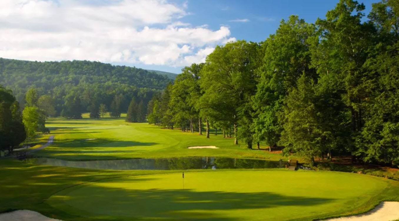 Panoramic view of The Cascades Course at The Omni Homestead Resort with lush green fairways and mountains in the background