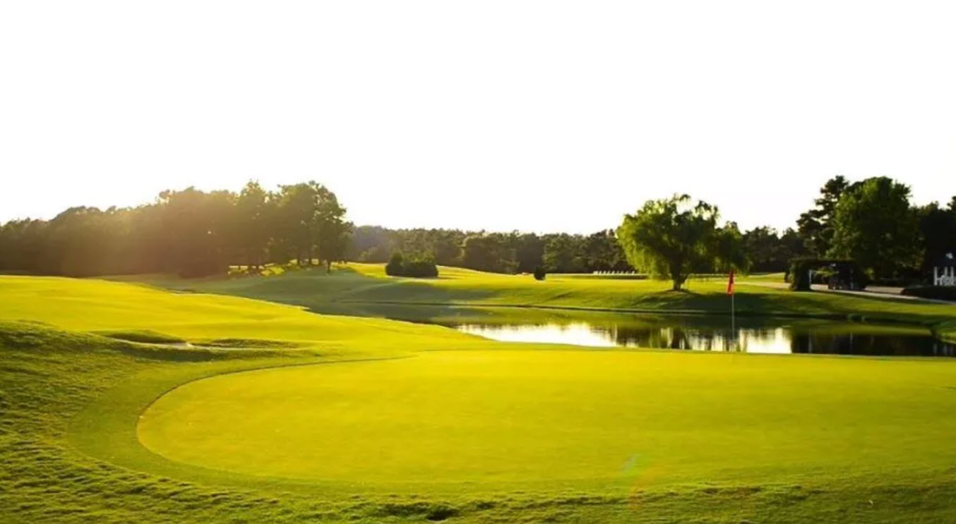 Aerial view of a lush green golf course at Porters Neck Country Club with water hazards and trees under a clear sky