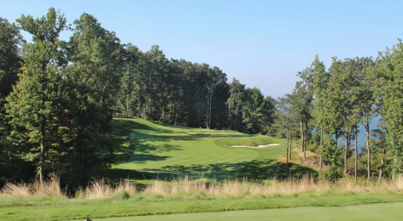 Aerial view of Primland Highland Course with lush green fairways winding through the Blue Ridge Mountains under a clear sky.