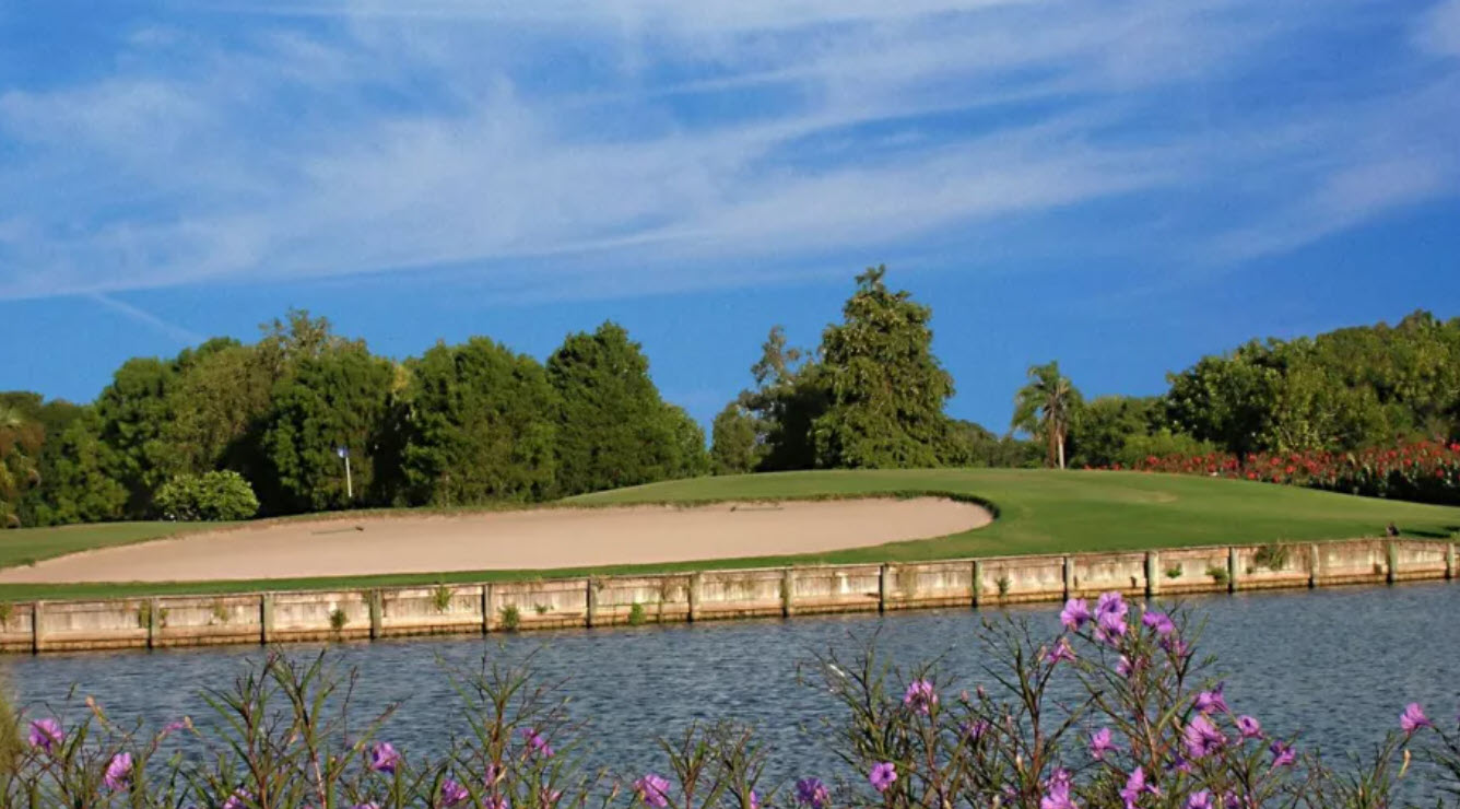 Overview of a green and fairway at Seminole Lake Country Club with mature trees and a lake in the background