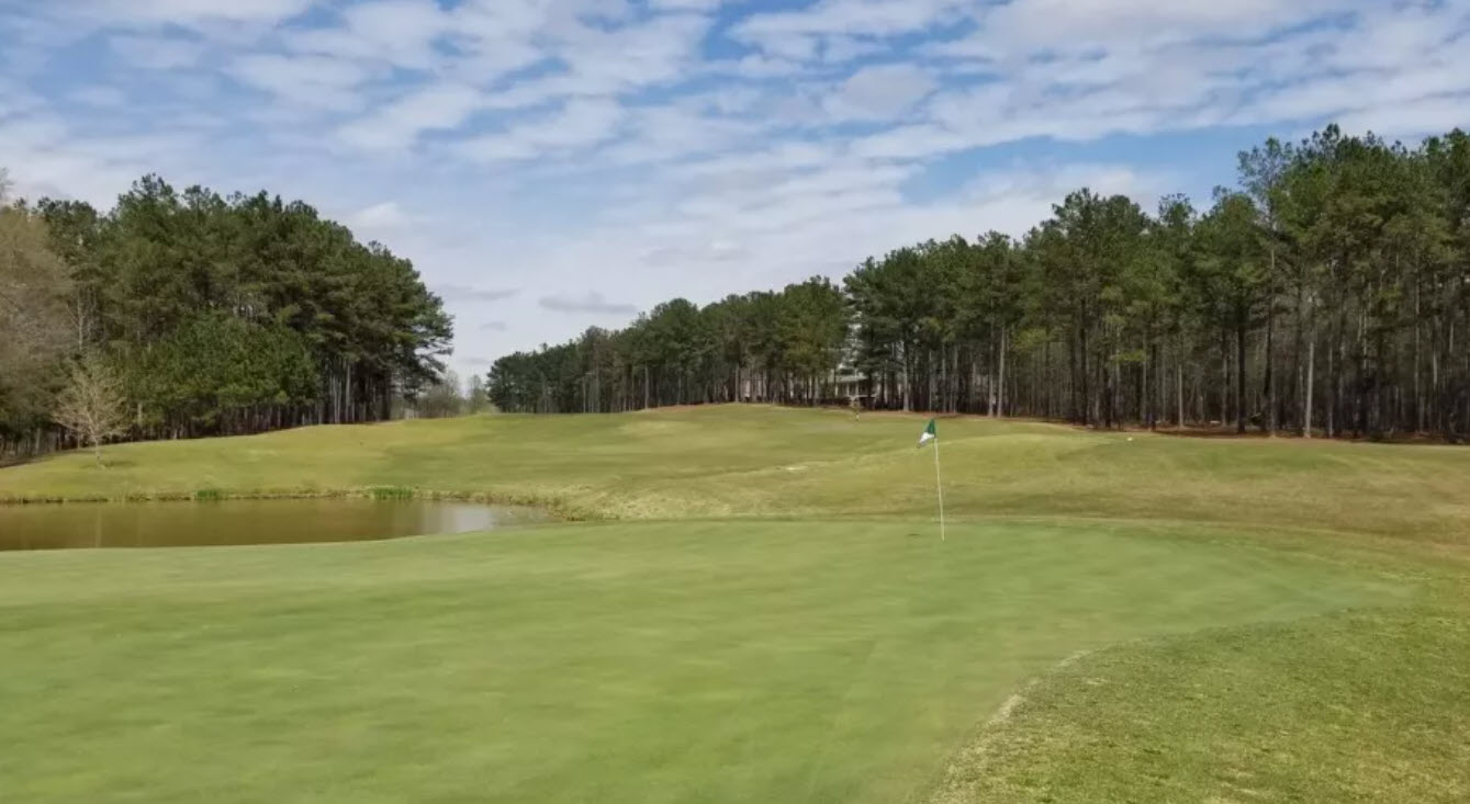 Panoramic view of The Frog Golf Club's lush green fairways and pristine bunkers under a clear blue sky