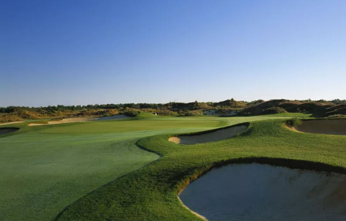 Panoramic view of the fescue-lined fairways and dramatic dunes at Twisted Dune Golf Club under a partly cloudy sky.