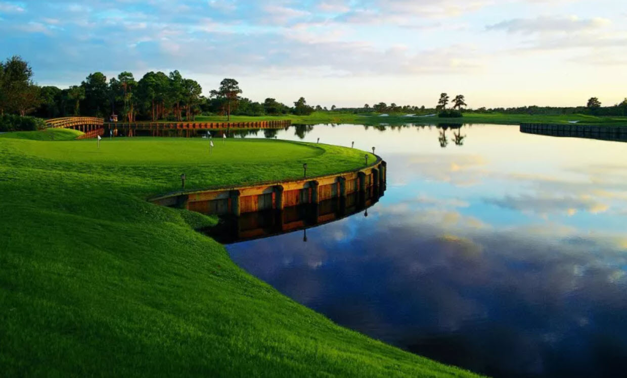 Lush green fairway with a water hazard and palm trees at University Park Country Club golf course