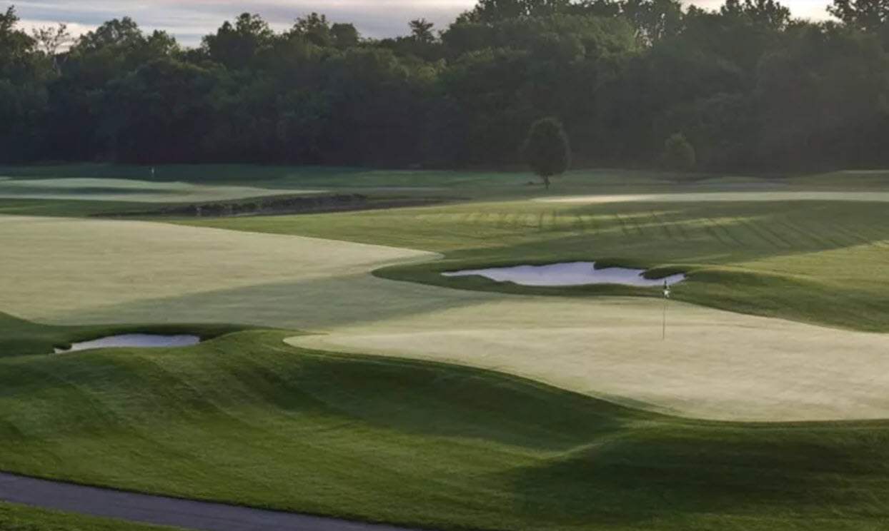 Scenic view of the golf course at Whitemarsh Valley Country Club with lush green fairways and mature trees under a clear sky.