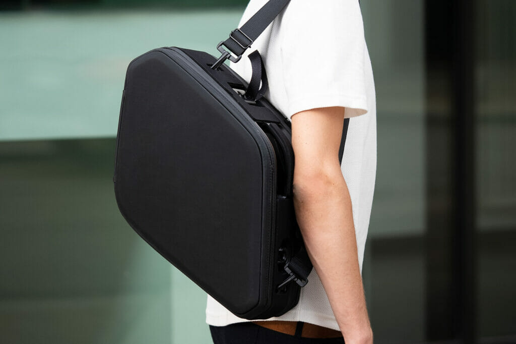 A woman is carrying a black backpack on her back.