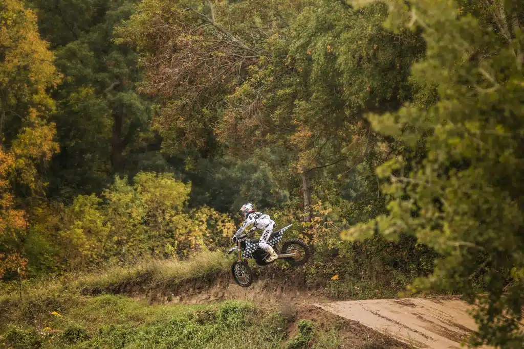 A person riding an Auto Draft dirt bike in the woods.