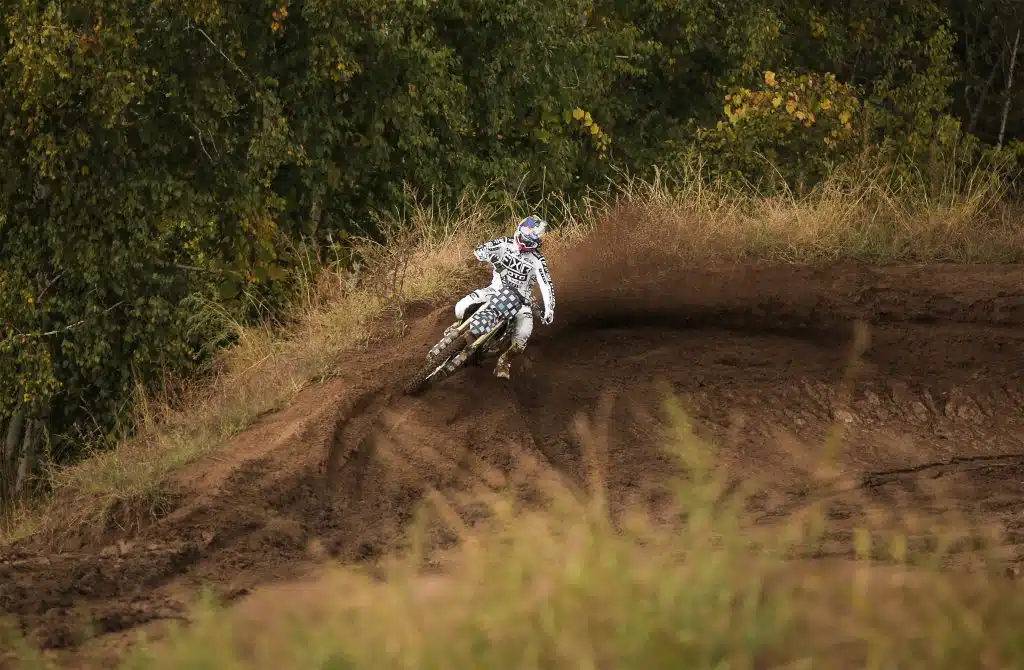 A person enthusiastically riding a dirt bike down a steep hill, enjoying the adrenaline rush.