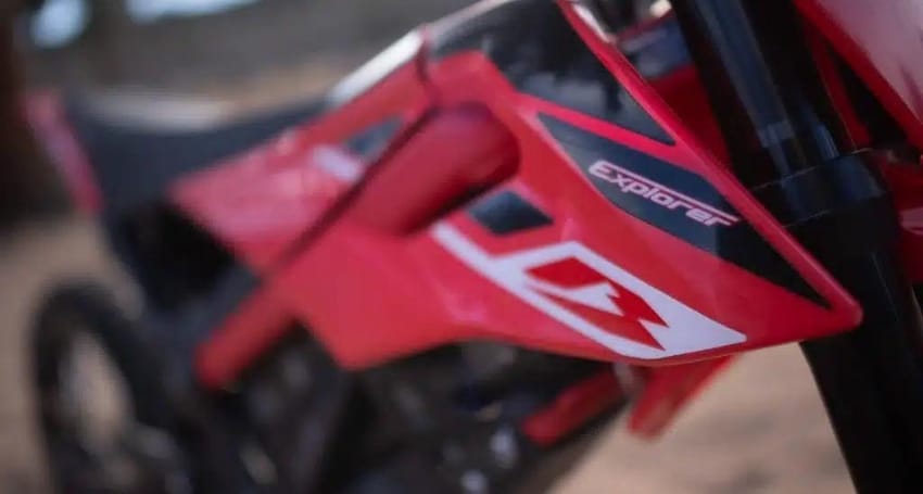 A red dirt bike is parked in the dirt.