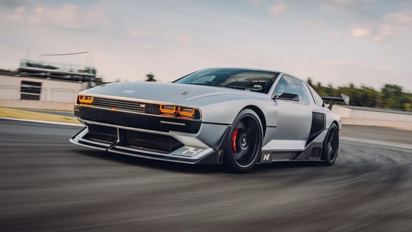 A silver sports car driving on a race track.