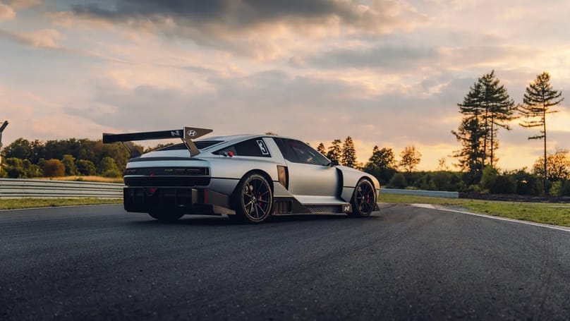 A porsche rs3 gt3 on a race track at sunset.